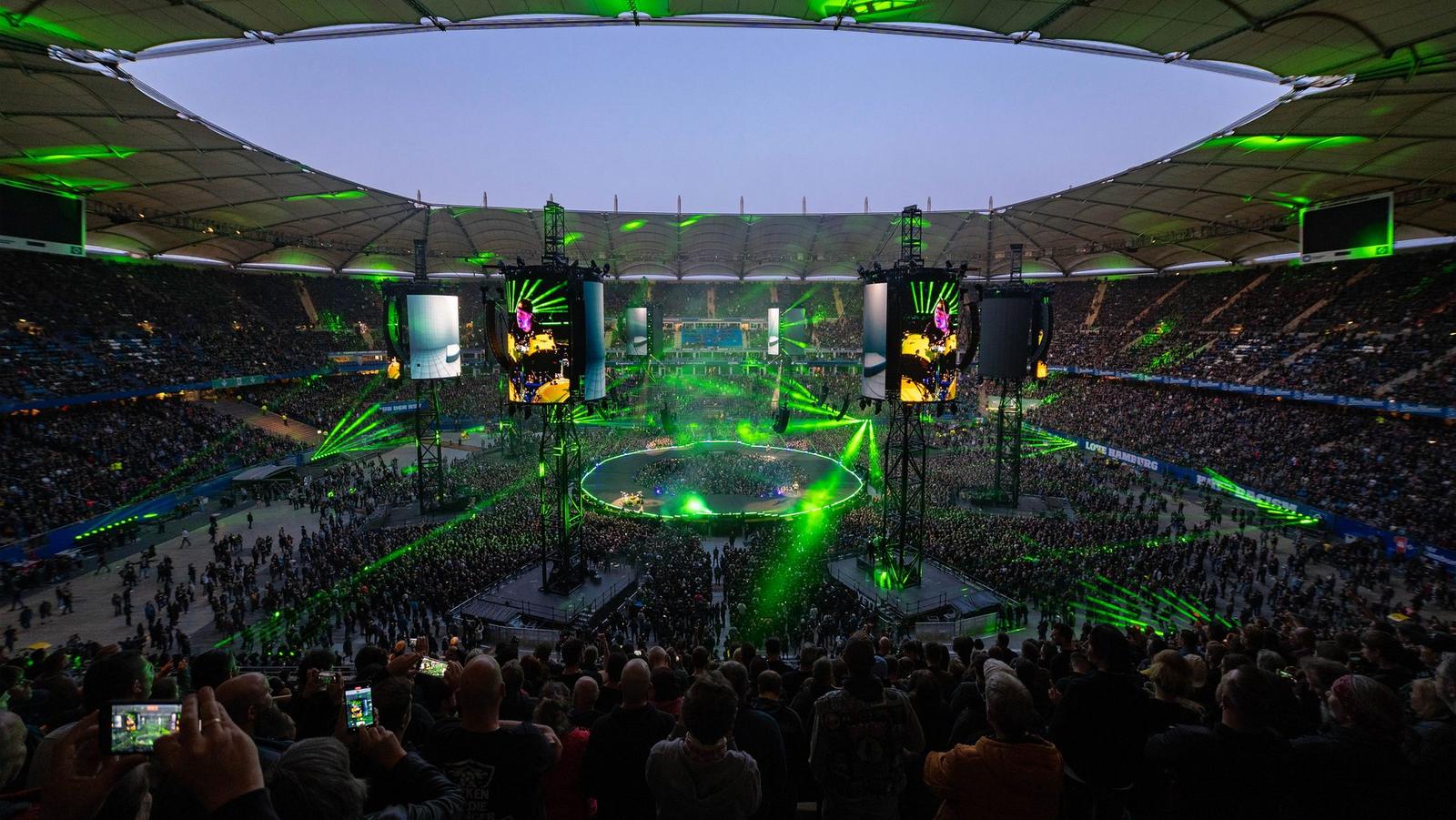 Bright green laser beams crossing an open-roof Metallica stadium show