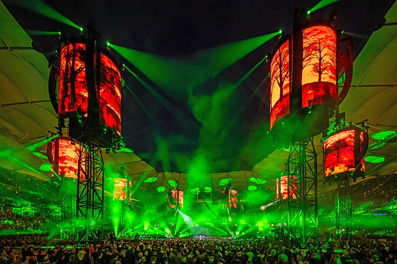 Green stage lighting and red video towers surrounding Metallica's circular stage